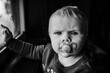 © Cavan Images - Black and white toddler face with pacifier in window light