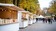 © Preecha - A panoramic view of a festive outdoor event such as a holiday market or festival showcasing numerous stalls and booths, all adorned with colorful lights. Attendees are visible enjoying the festive