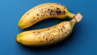 © Alfazet Chronicles - Two ripe bananas with brown spots on a blue background, showcasing the natural ripening process and texture of the fruit.