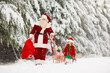 © famveldman - Kids and Santa with Christmas gifts in snow forest