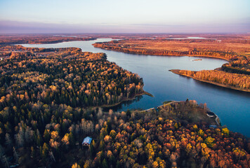 Wall Mural - Aerial drone view of cottage or log cabin in autumn colors forest by blue lake. Beautiful landscape