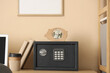 © Pixel-Shot - Safe box with piggy bank and books on commode near beige wall at home, closeup