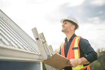 Wall Mural - man with hard hat standing on steps inspecting house roof