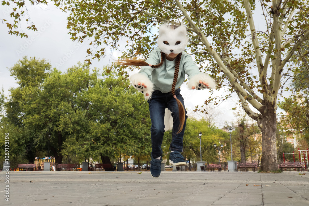Quadrober girl with cat mask jumping in park