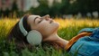 © Vitalii Shkurko - A young woman lies back on green grass in a park, eyes closed, enjoying her music through headphones as the warm sunlight bathes her surroundings