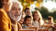 © Lens Legacy - A joyful family scene showing a senior man surrounded by family members, enjoying coffee outdoors amidst colorful autumn leaves, depicting warmth and togetherness.