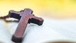 © KPD - Dark red wooden cross leaning against an old open book symbolizing the spread of Jesus Christs love among Christians reflecting faith devotion and the importance of Christian teachings.