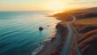 © Chatchanan - Aerial shot of a scenic coastal road at sunset, the ocean sparkling under the golden light, realistic
