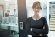 © peopleimages.com - Arms crossed, doorway and portrait of business woman in office for job opportunity or start of internship. Confident, glasses and serious with assertive employee at entrance to workplace for ambition