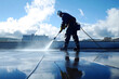 © Di Studio - professional cleaner cleaning rooftop of modern building with high pressure machine over blue sky background