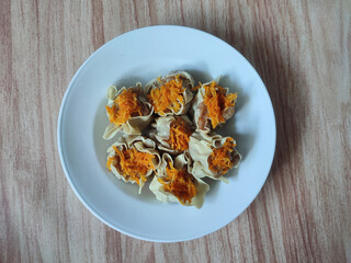 A close-up of dim sum garnished with shredded carrot, showcasing traditional Asian delicacies in an artistic presentation. Negative space