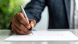 © somchairakin - Close up of hand signing document with pen, conveying professionalism and focus