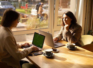 сowork, two women work at laptops in a cafe