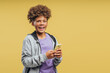© Maria Vitkovska - Cheerful, happy African American boy with curly hair wearing stylish hoodie, holding mobile phone