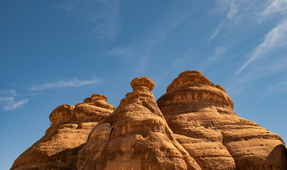 Round cone shaped monoliths against a blue sky and clouds in Hegra near Al Ula Saudi Arabia