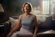 © Markus Schröder - Portrait of a jovial woman in her 50s dressed in a breathable mesh vest on crisp minimalistic living room
