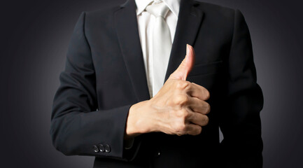 A businessman in a suit gives a thumbs up showing confidence.