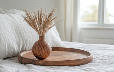 An elegant close-up shot of a wooden tray holding a vase of dried grass, set on a pristine white bed within a beautifully designed bedroom. 