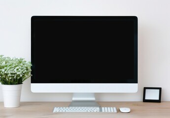 A modern computer with a blank screen on a wooden desk A white flowerpot is in the left corner and a black photo frame on the right The desk is in a clean and minimalist environment