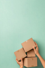 Wall Mural - Hands holding cardboard shipping boxes on plain color background, copy space