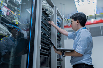 Computer engineer is setting up network in server room,Systems Maintenance Technician,Male engineer working in server room at modern data center
