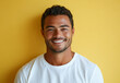 © Arif - Portrait of a cheerful man with a bright smile, wearing a white shirt and standing against a vibrant yellow background.
