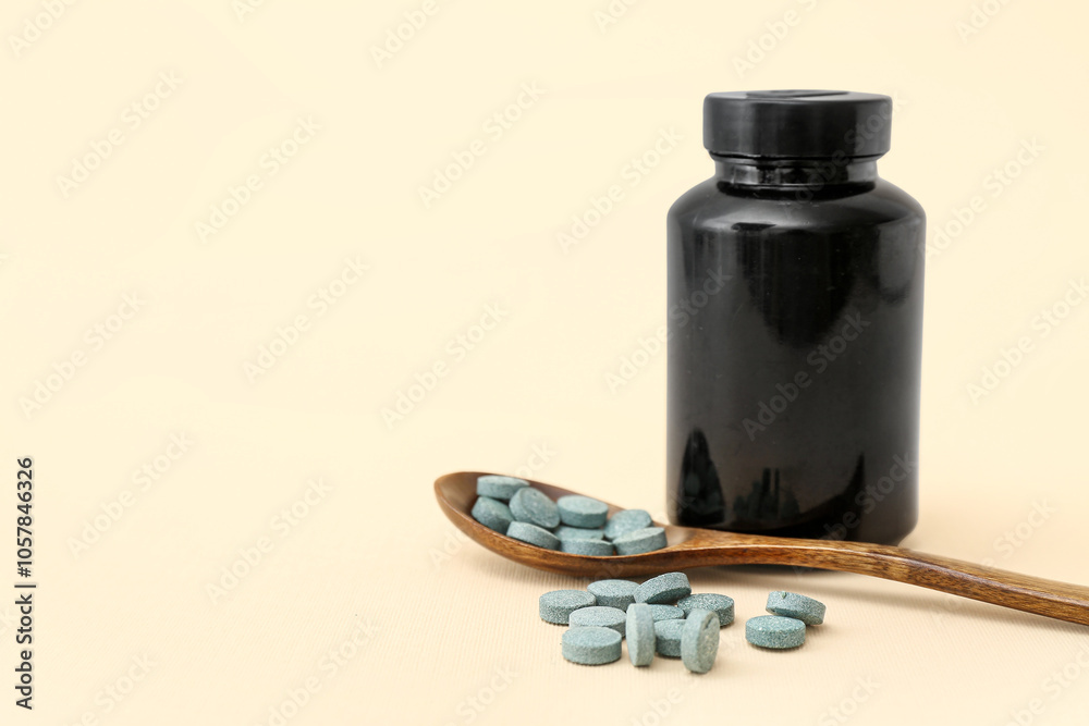 Bottle and wooden spoon with pills on beige background