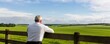 © LIPO@SEXTAO22 - Investor leaning on a wooden fence, observing distant farmland