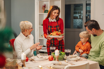 Wall Mural - Happy family celebrating christmas eve holding roast turkey for dinner