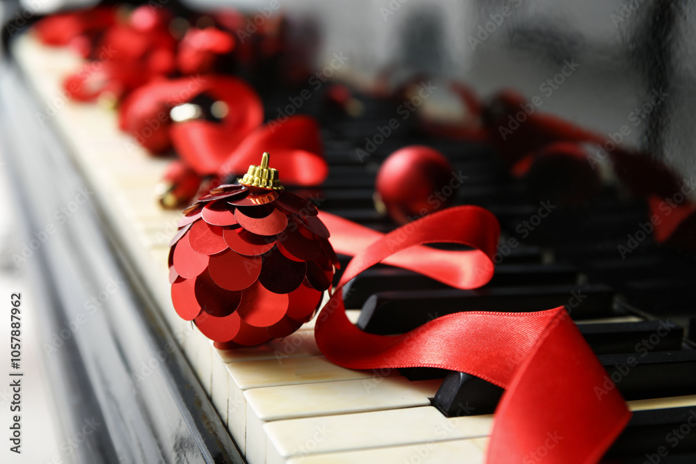 Christmas balls with red ribbon on piano keys. Closeup