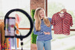 © deagreez - Photo of cheerful lovely girl popular blogger selling clothes on video streaming live broadcast daylight indoors