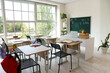 © Pixel-Shot - Interior of empty classroom with school desks and text BACK TO SCHOOL on chalkboard