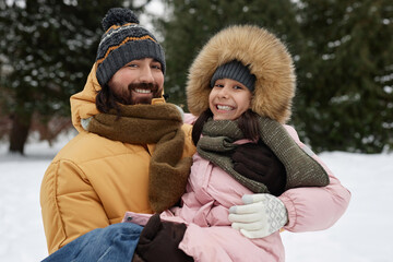 Wall Mural - Waist up portrait of happy father holding daughter while playing together outdoors in winter and smiling at camera joyfully