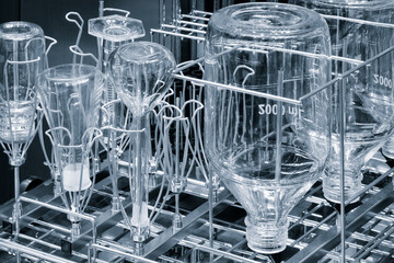 Poster - A rack of glassware is being washed in a dishwasher. The glassware includes a variety of bottles and cups, some of which have numbers on them