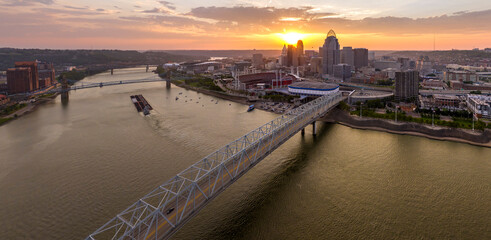 Driving cars on bridge highway near illuminated high skyscraper buildings in downtown district of Cincinnati, Ohio, USA. American city with business financial district at sunset