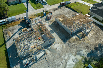 Wall Mural - Professional builders and crane truck working on roof construction of unfinished suburban home with wooden frame structure in Florida rural area. Concept of housing development in America