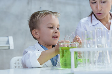 Woman and child boy in science class analyzing experiment by mixing chemical liquid in glass, Science kids modern technology education concept, 