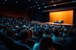 © khalid_spk - A large audience sits in a darkened auditorium, facing a brightly lit stage where a presentation