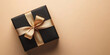 © AspctStyle - Elegant black gift box with gold ribbon on beige background. A stylish black gift box wrapped with a satin gold ribbon and bow, set against a beige background, creating a luxurious and minimalist