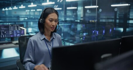 Poster - Asian Woman with Headphones Having a Conversation on a Call while Working on Her Computer in Data Center Office. Specialist Collaborating with the Team on Network Security Adjustments