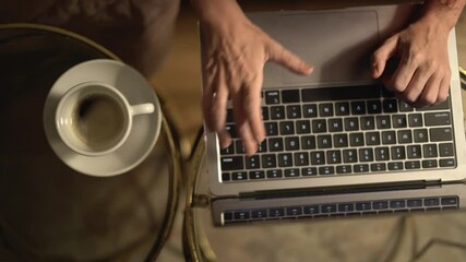Leinwandbilder - This image captures a closeup view of hands actively typing on a laptop while a cup of coffee rests nearby, set against a cozy and ambient environment that promotes productivity and creativity