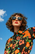 © Rohit k  - Stylish model showcases a trendy look, wearing fashionable sunglasses and a vibrant floral shirt while posing against a clear blue sky, exuding confidence and summer vibes