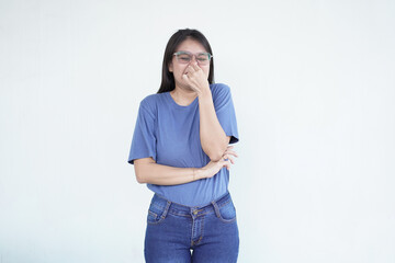 beautiful Asian woman shows a wrinkled nose in reaction to a smell while covering her nose against a white background