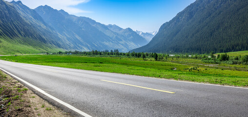 Sticker - Countryside asphalt road and green meadow with mountains nature landscape on a sunny day. Road trip.