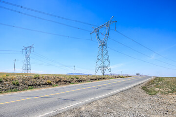 Asphalt highway road and high voltage power tower landscape. road trip.