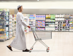 Poster - Young muslim man walking and pushing a shopping cart at a supermarket