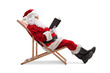 © Ljupco Smokovski - Santa claus sitting on a beach chair and reading a book