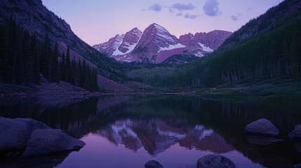 Majestic mountain peaks reflected in a still lake at dusk, with a hint of pink in the sky.