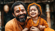 © Alfazet Chronicles - Smiling man and child wearing traditional festive attire with flower garlands, highlighting cultural celebrations. Both have orange attire and facial decorations.