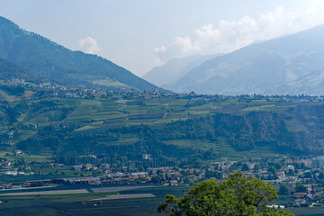 Aerial view of Etsch Valley at South Tyrol with orchards and Italian City of Meran in the background on a sunny summer day. Photo taken July 19th, 2024, Merano Meran, Italy.